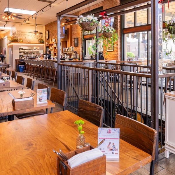 A restaurant interior with wooden tables, a bar area, and a staircase leading to another level.