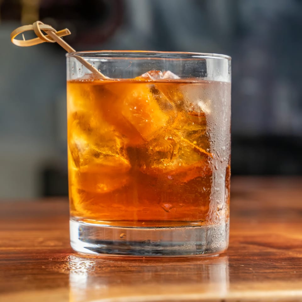 A Union American cocktail with ice and a decorative pick, condensation on the glass.