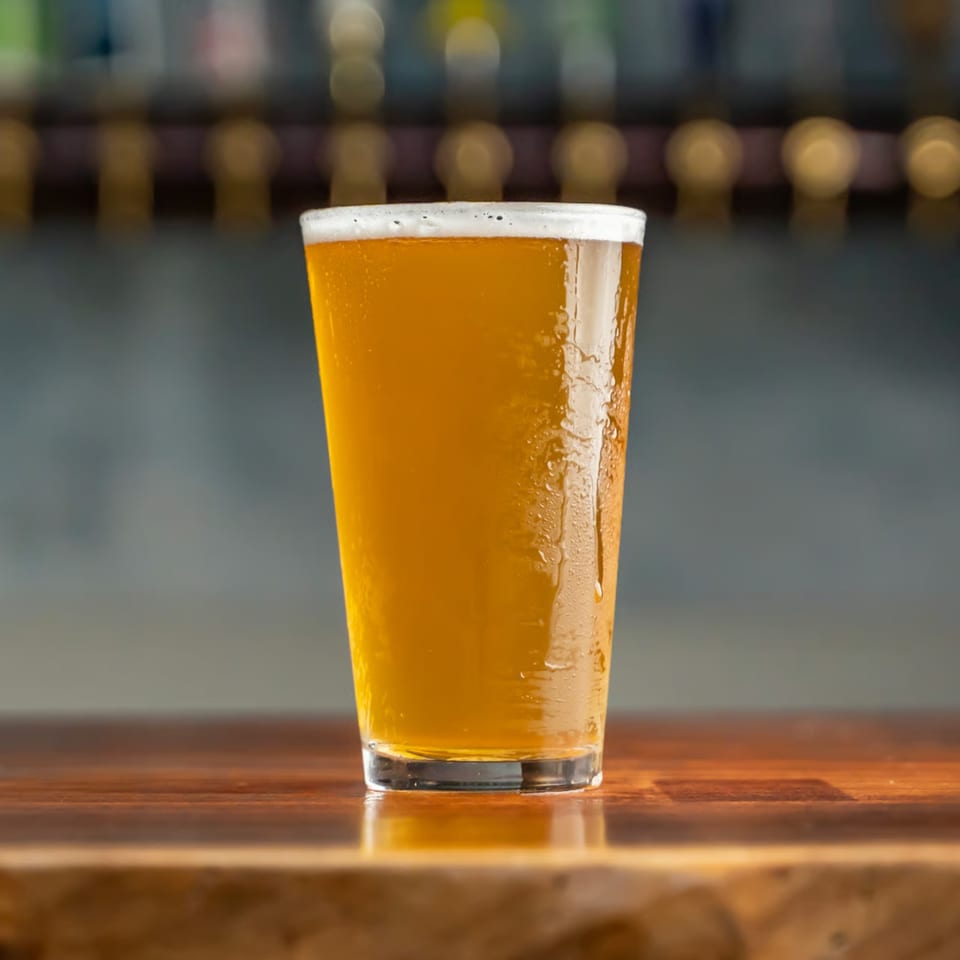 A cold glass of Union's American beer with condensation, sitting on a wooden bar.