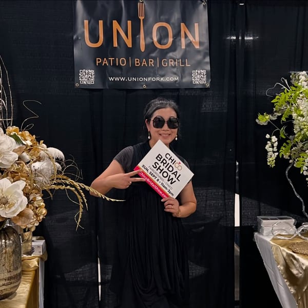 A woman in sunglasses holds a "Chico Bridal Show" sign in front of a Union restaurant banner.
