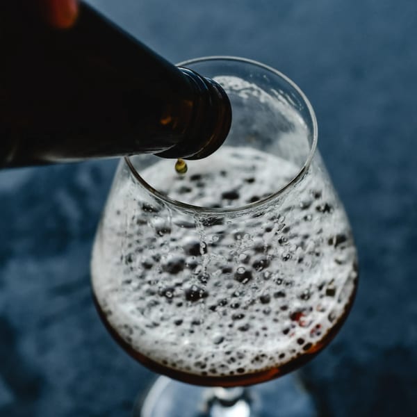 A bottle pouring Union's American beer into a glass, creating a foamy head.