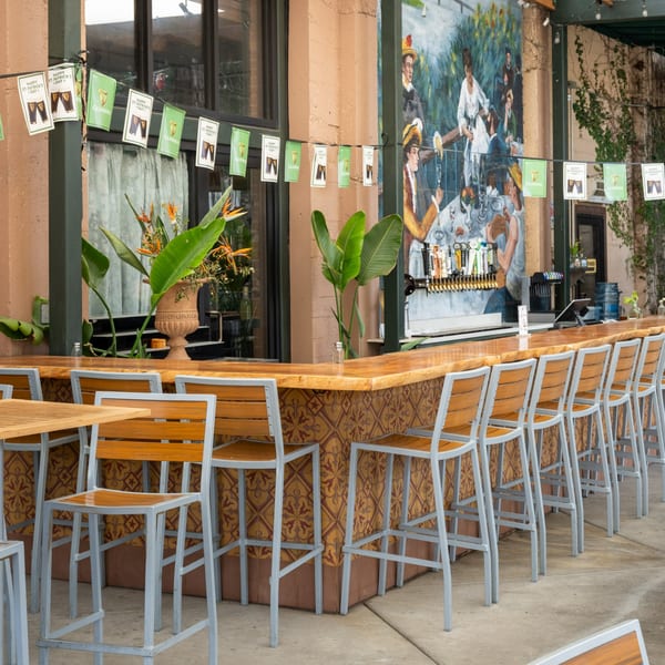 Outdoor bar with St. Patrick's Day decorations, bar stools, and a mural on the wall.