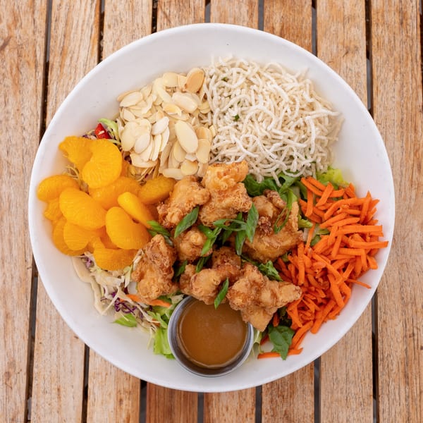 Overhead view of a vibrant Asian chicken salad with crispy chicken, mandarin oranges, and almonds.