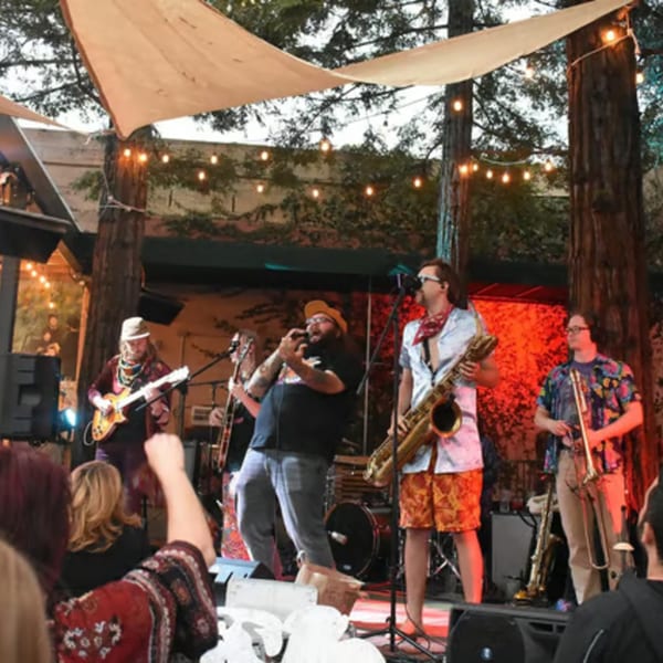 A band performs on an outdoor stage at Union, with string lights and trees overhead.
